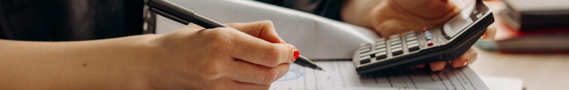 Person holding a calculator and writing results on paper.